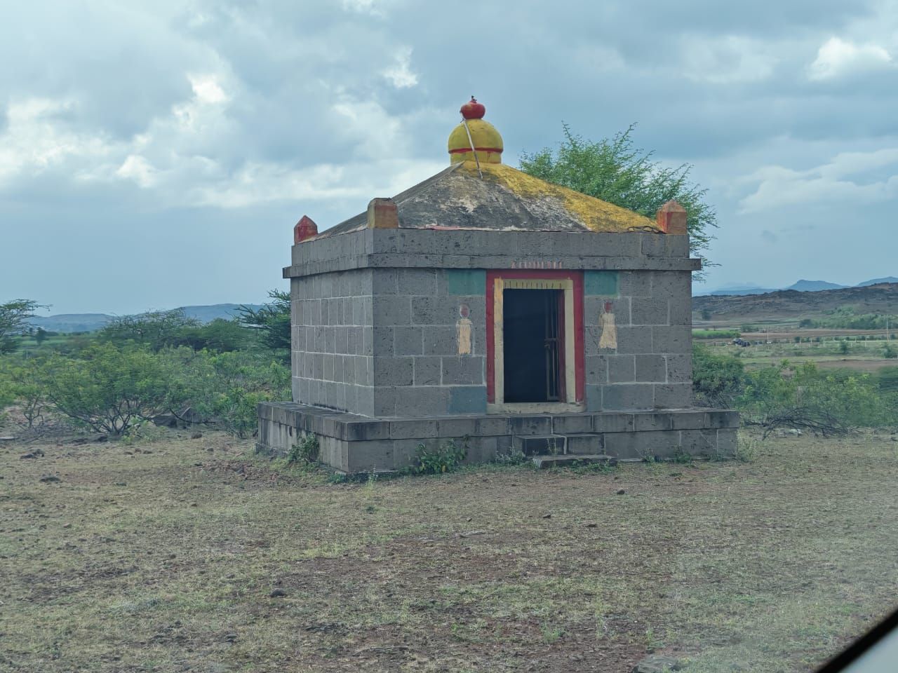 A small stone shrine with a yellow dome beside the track